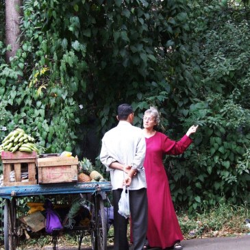 Osho-Besucherin in langer roter Robe in Koregaon Park mit indischem Obsthändler