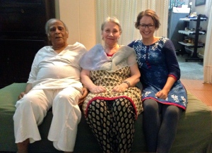 Älterer Mann in weißem Hemd sitzt mit seiner Frau und einer jüngeren Frau auf einem grünen Sofa 